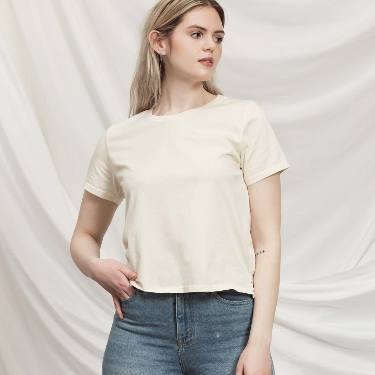 Woman wearing an off-white cotton t-shirt.